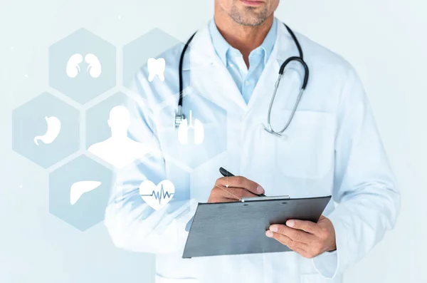 Cropped image of doctor with stethoscope on shoulders writing something in clipboard isolated on white with medical interface — Stock Photo