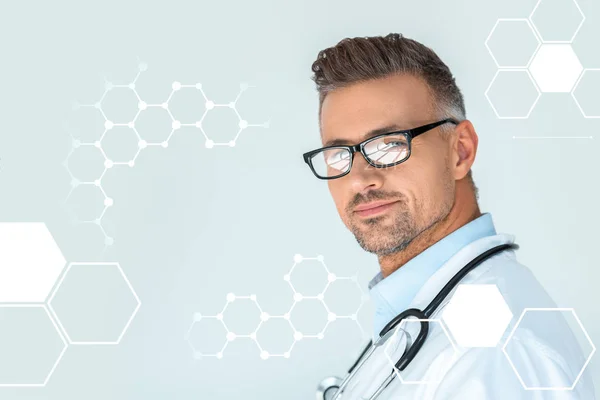 Портрет красивого врача в очках со стетоскопом на плечах, смотрящего на камеру, изолированную на белом с медицинской символикой — стоковое фото