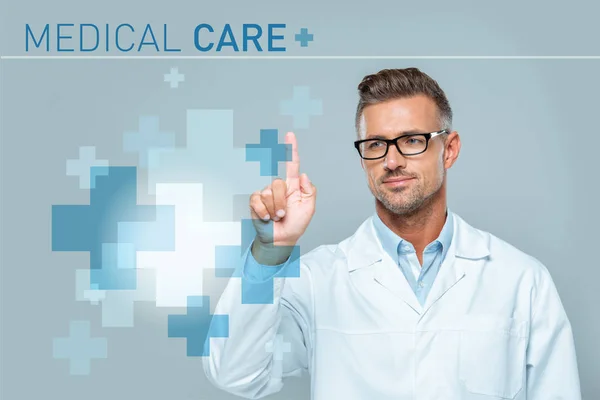 Handsome scientist in white coat and glasses touching medical care interface in air isolated on grey, artificial intelligence concept — Stock Photo