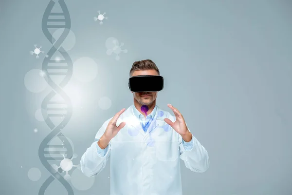 Вчений у гарнітурі віртуальної реальності тримає щось ізольоване на сірому з ДНК, концепція штучного інтелекту — стокове фото