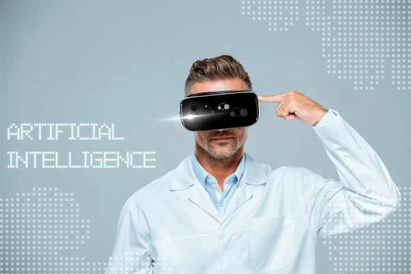 Scientist  in virtual reality headset pointing on his head isolated on grey, artificial intelligence concept — Stock Photo