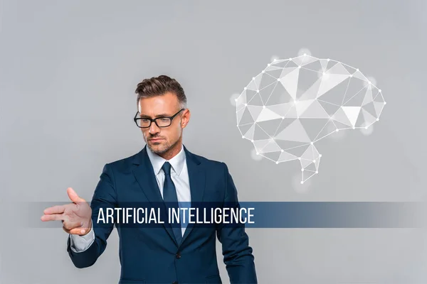 Handsome businessman in glasses pointing on something artificial intelligence lettering — Stock Photo