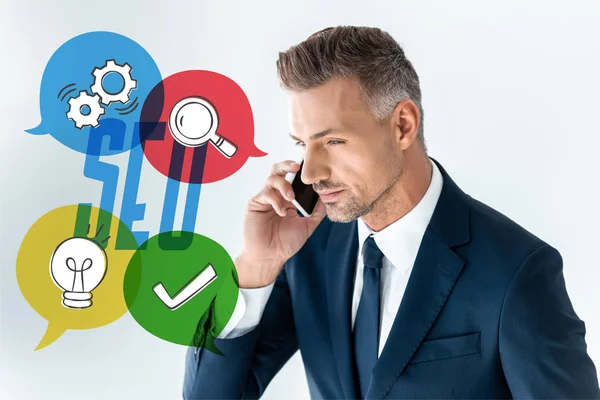 Portrait of handsome businessman talking by smartphone isolated on white with seo icons — Stock Photo