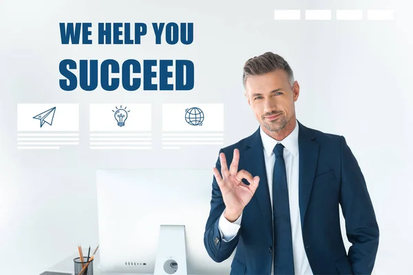 Handsome businessman showing okay gesture and looking at camera isolated on white with