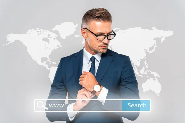 Bel homme d'affaires portant une montre-bracelet et regardant loin isolé sur gris avec carte du monde et barre de recherche — Photo de stock