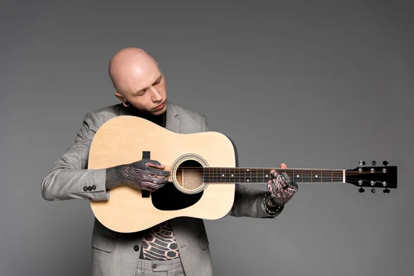 Bonito careca tatuado homem no terno tocando violão isolado no cinza — Fotografia de Stock