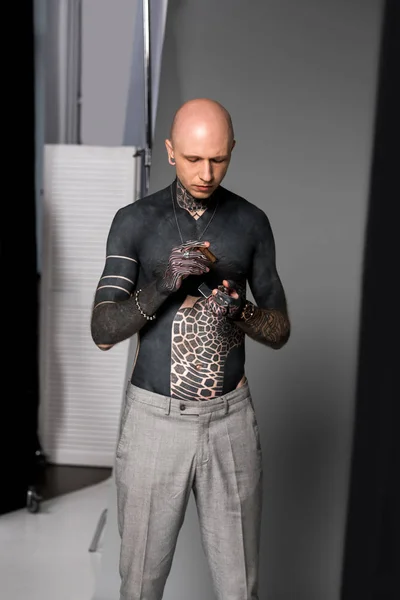 Careca sem camisa tatuado homem segurando isqueiro e charuto enquanto em pé no estúdio — Fotografia de Stock