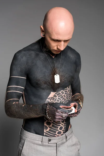 Homme à poitrine nue avec tatouages tenant boîte à cigarettes isolé sur gris — Photo de stock