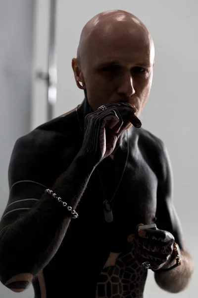 Handsome shirtless man with tattoos smoking cigar and looking at camera — Stock Photo