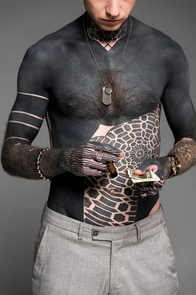 Plan recadré d'un homme tatoué tenant un cigare et des billets en dollars isolés sur du gris — Photo de stock