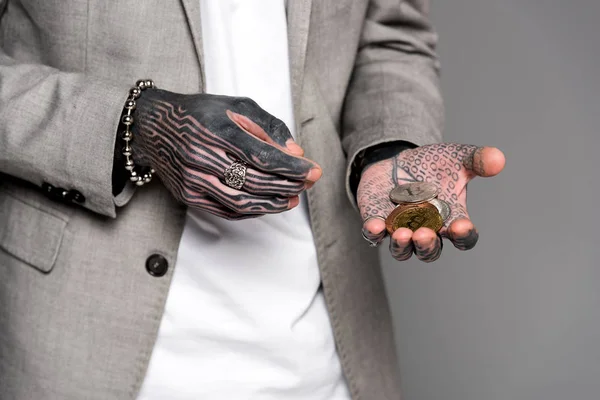 Cropped shot of tattooed man in suit jacket holding bitcoins isolated on grey — Stock Photo