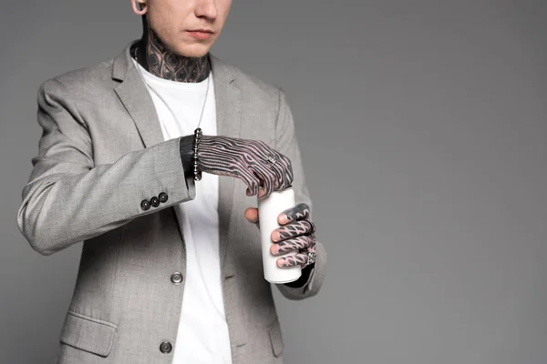 Cropped shot of tattooed man in suit jacket opening aluminum can isolated on grey — Stock Photo