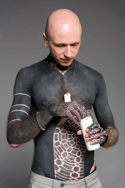 Bare-chested bald man with tattoos opening soda can isolated on grey — Stock Photo
