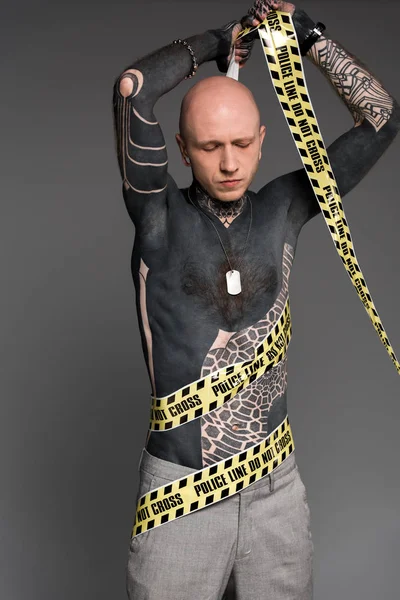 Bald shirtless tattooed man wrapping himself with cross line isolated on grey — Stock Photo