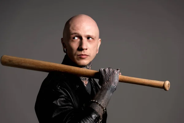 Bald tattooed man in leather jacket holding baseball bat and looking away isolated on grey — Stock Photo