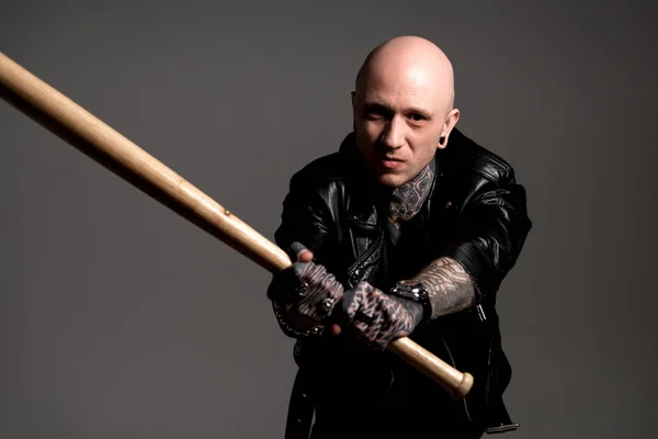 Aggressive tattooed man in leather jacket holding baseball bat and looking at camera isolated on grey — Stock Photo