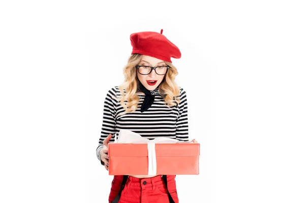 Femme blonde surprise en béret rouge regardant boîte cadeau isolé sur blanc — Photo de stock