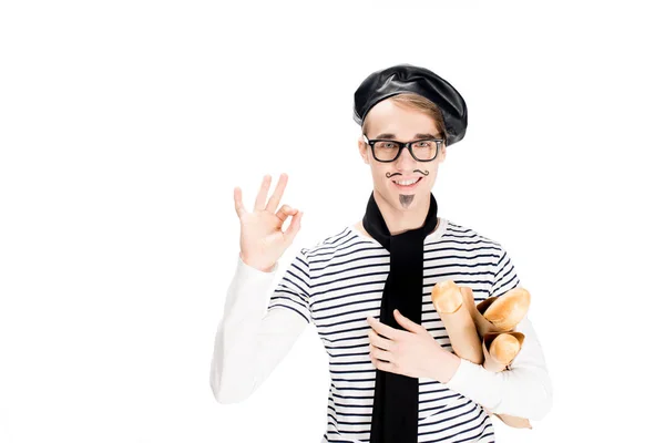 Smiling french man holding tasty baguettes and showing ok sign isolated on white — Stock Photo