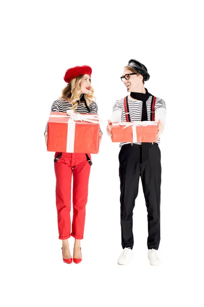 Hombre francés y mujer atractiva mirándose mientras sostiene cajas de regalo aisladas en blanco - foto de stock