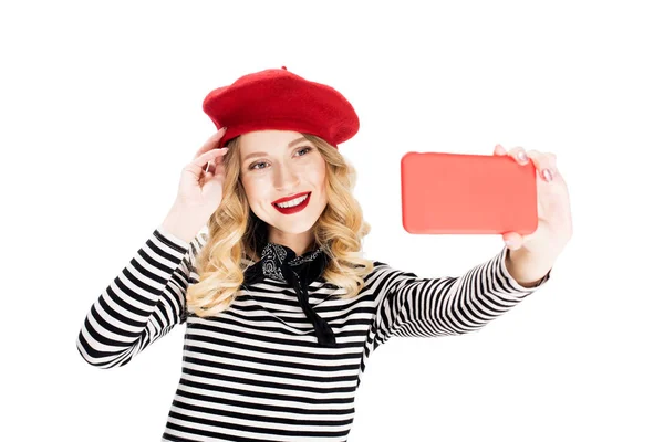 Счастливая француженка в красном берете делает селфи на смартфоне изолированный на белом — стоковое фото