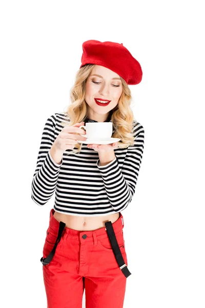 Attraktive Frau in roter Baskenmütze mit Tasse Kaffee in den Händen isoliert auf weiß — Stockfoto