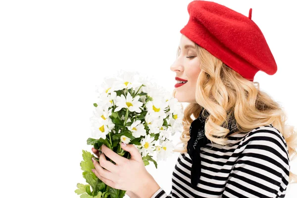 Hermosa mujer en boina roja sonriendo mientras huele flores aisladas en blanco - foto de stock