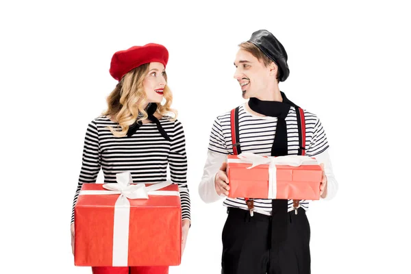 Cheerful couple holding gift boxes and looking at each other isolated on white — Stock Photo