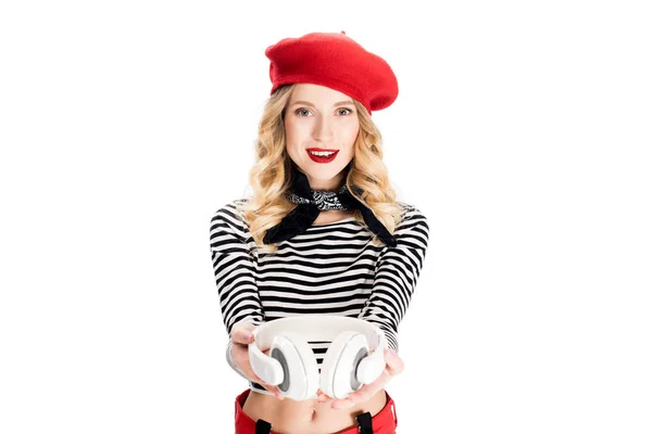 Attraktive Frau mit roter Baskenmütze und Kopfhörer in den Händen isoliert auf weiß — Stockfoto