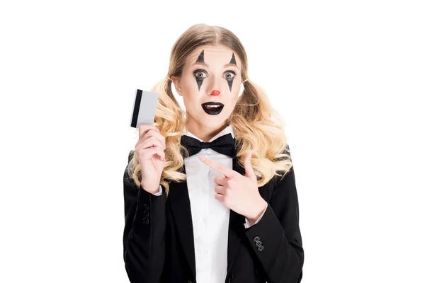 Cheerful female clown pointing with finger at credit card  isolated on white — Stock Photo