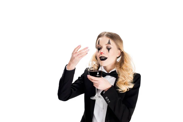 Payaso femenino en traje oliendo vino mientras sostiene el vidrio aislado en blanco - foto de stock