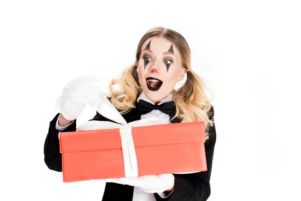 Excited female clown holding gift box isolated on white — Stock Photo
