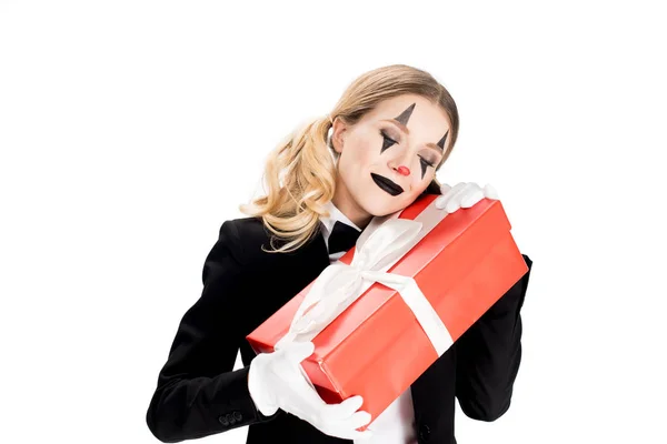 Excited female clown embracing gift box isolated on white — Stock Photo