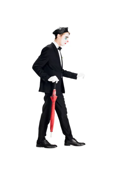 Clown in suit and black beret holding umbrella while walking isolated on white — Stock Photo