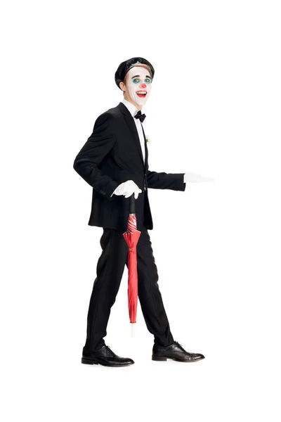 Joyeux clown en costume et béret noir tenant parapluie tout en marchant isolé sur blanc — Photo de stock