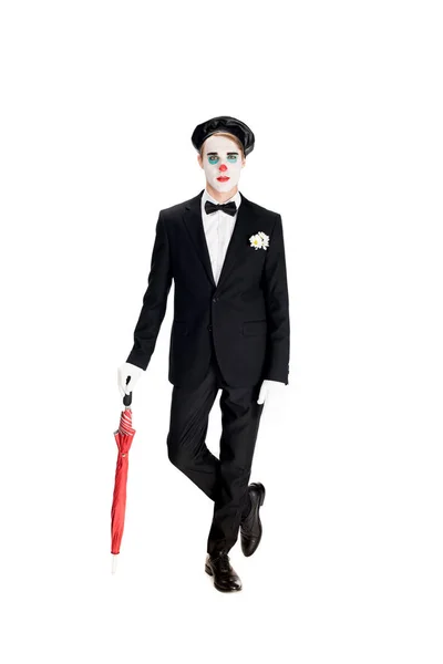 Ernster Clown in Anzug und schwarzer Baskenmütze mit Regenschirm, während er isoliert auf weiß steht — Stockfoto
