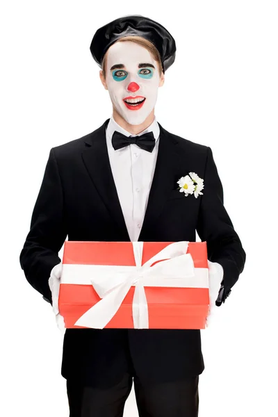 Glücklicher Clown hält Geschenkbox, während er im Anzug isoliert auf weiß steht — Stockfoto