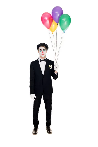 Payaso triste en traje y boina negra sosteniendo globos de helio aislados en blanco - foto de stock