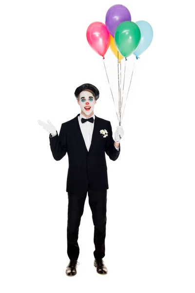 Palhaço sorridente em terno e boina preta segurando balões de hélio isolado em branco — Fotografia de Stock