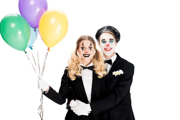 Happy clowns hugging and holding helium balloons isolated on white — Stock Photo
