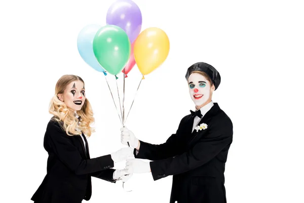 Clown heureux donnant des ballons à la femme en costume isolé sur blanc — Photo de stock