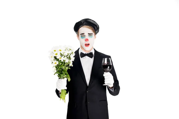 Überraschter Clown mit Blumen und Glas auf Wein in den Händen isoliert auf weiß — Stockfoto