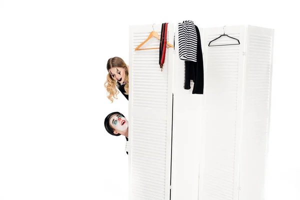 Surprised clowns looking at each other from dressing room door isolated on white — Stock Photo