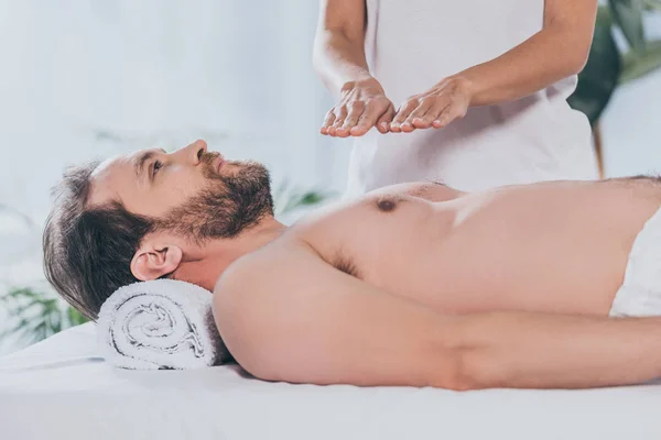 Cropped shot of peaceful bearded man receiving reiki treatment on bare chest — Stock Photo