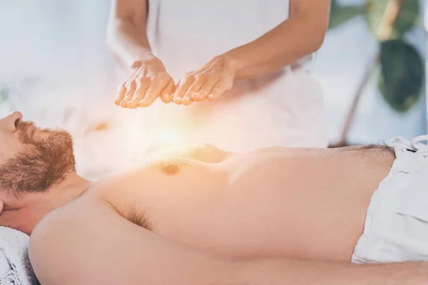 Cropped shot of bearded man receiving reiki treatment on bare chest — Stock Photo