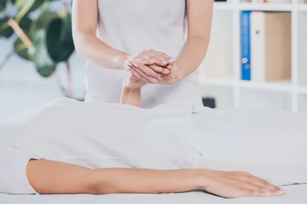 Cropped shot of reiki healer holding female hand during session — Stock Photo