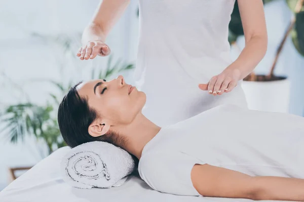 Cropped shot of calm young woman receiving reiki healing therapy on head and chest — Stock Photo