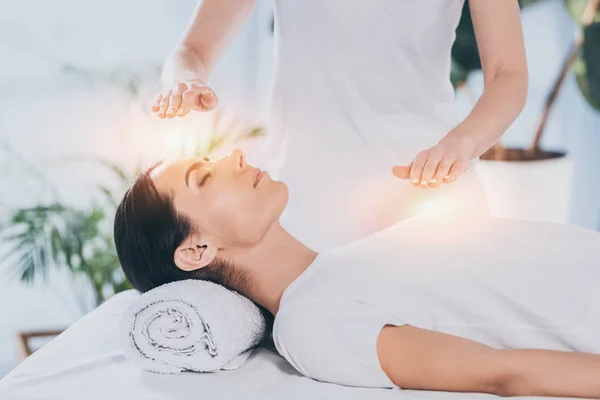 Side view of calm young woman receiving reiki healing therapy on head and chest — Stock Photo