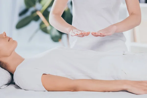 Cropped shot of calm young woman receiving reiki healing treatment on stomach — Stock Photo
