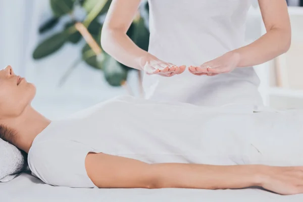 Tiro cortado de calma jovem mulher recebendo tratamento de cura reiki no estômago — Fotografia de Stock