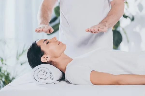 Tiro recortado de curandeiro do sexo masculino fazendo reiki sessão de tratamento para a jovem mulher com olhos fechados — Fotografia de Stock